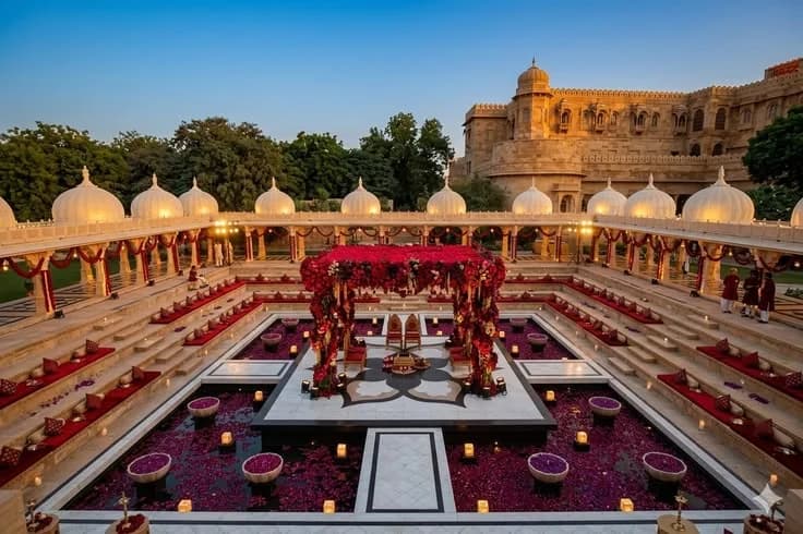 Palace courtyard wedding mandap with red floral canopy, petal-filled water channels and candle-lit terraces — destination wedding production by SatAns Production